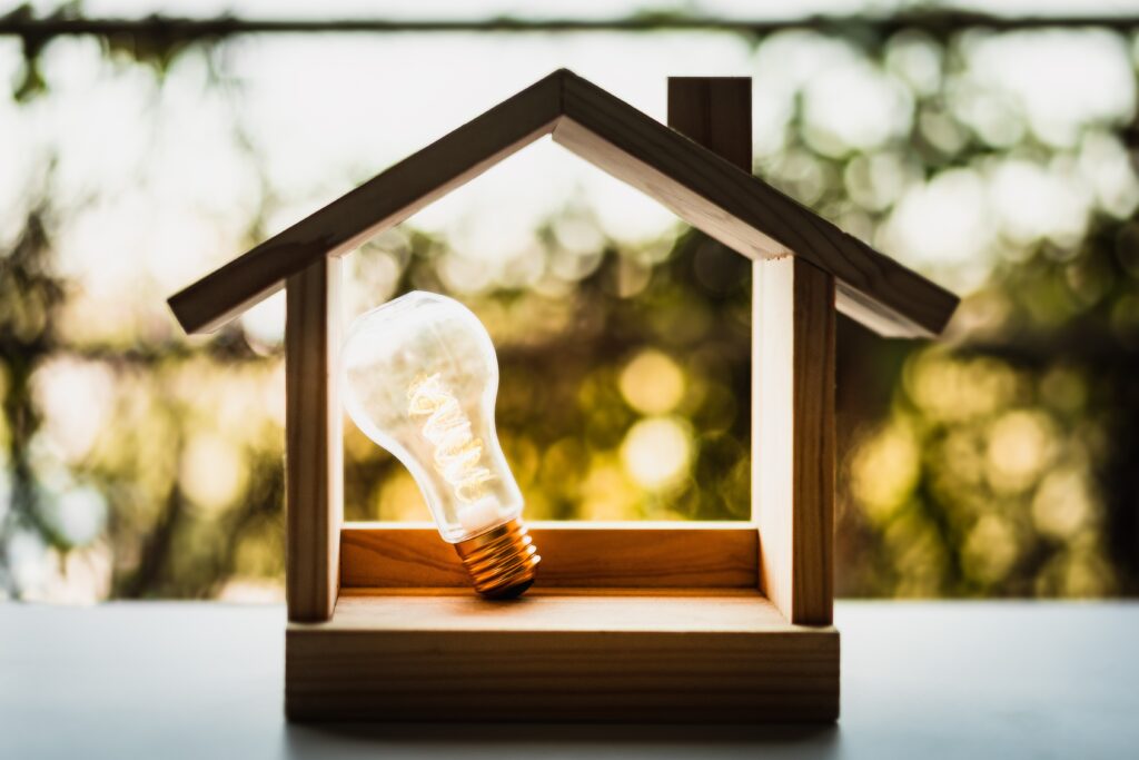 Light bulb with wood house on the table, a symbol for construction, Creative light bulb idea, power energy or business idea concept ecology, loan, mortgage, property or home.